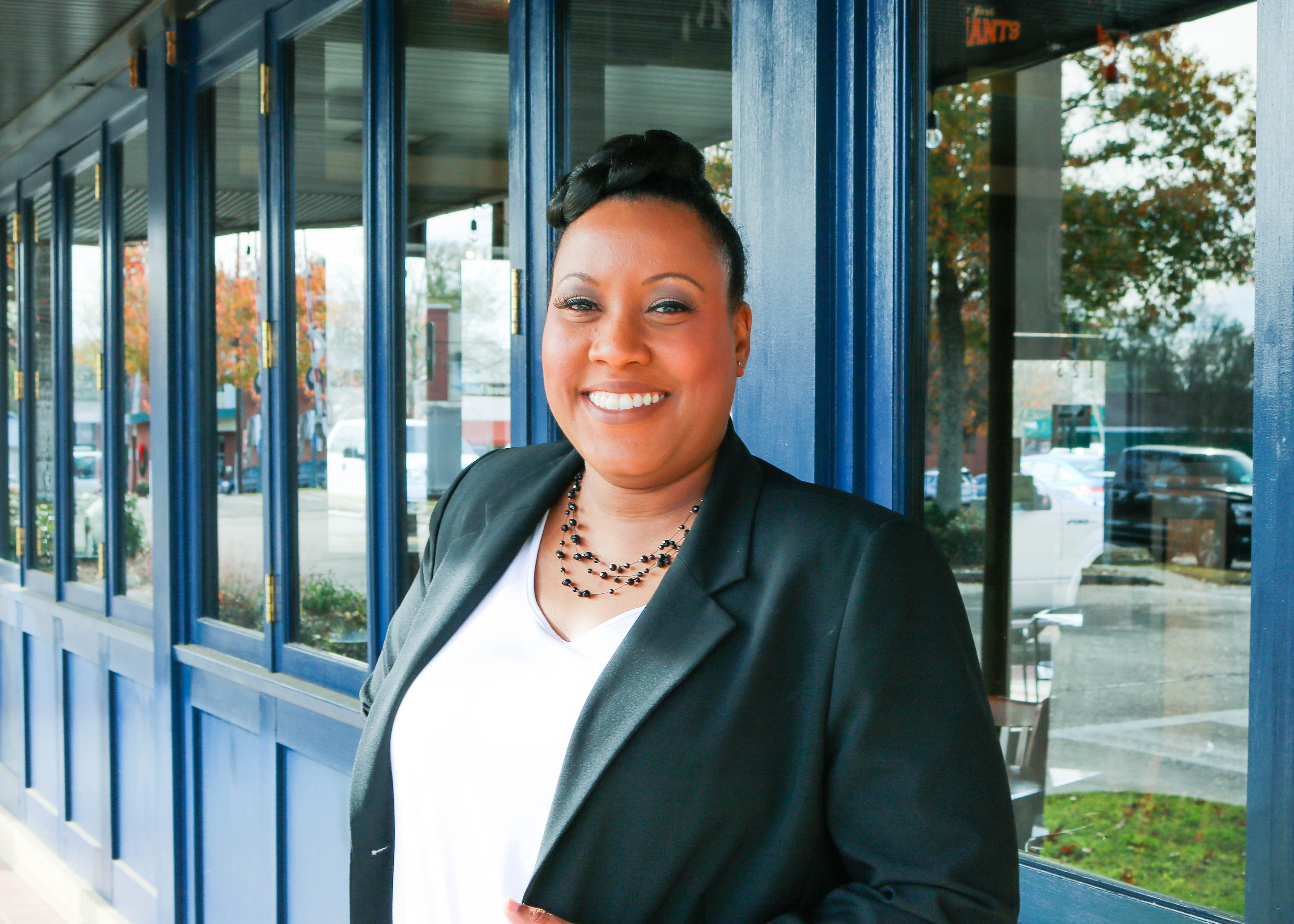 Christe Standing in front of windows with black blazer and white shirt