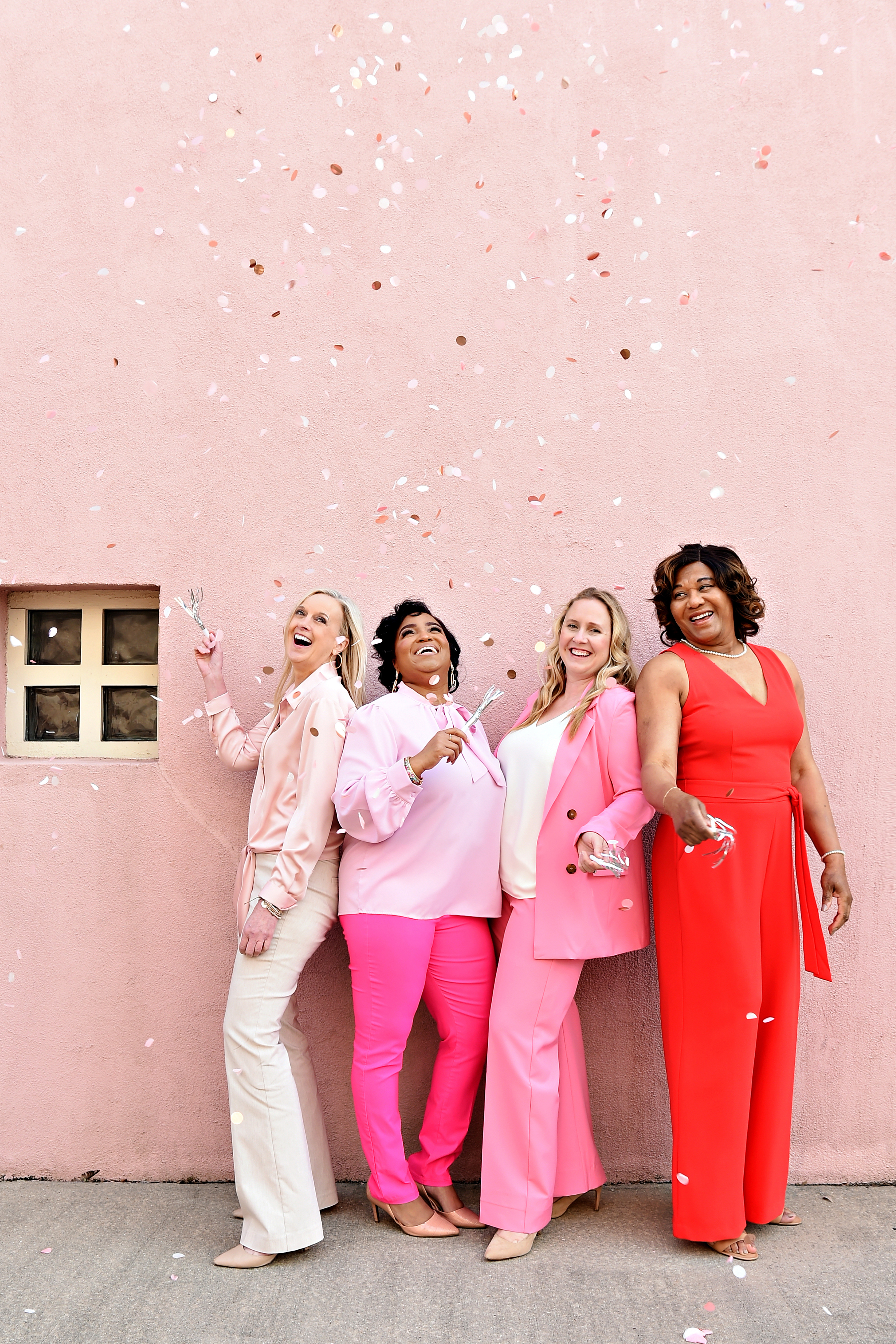 Ladies Standing in front of Pink Wall with Confetti