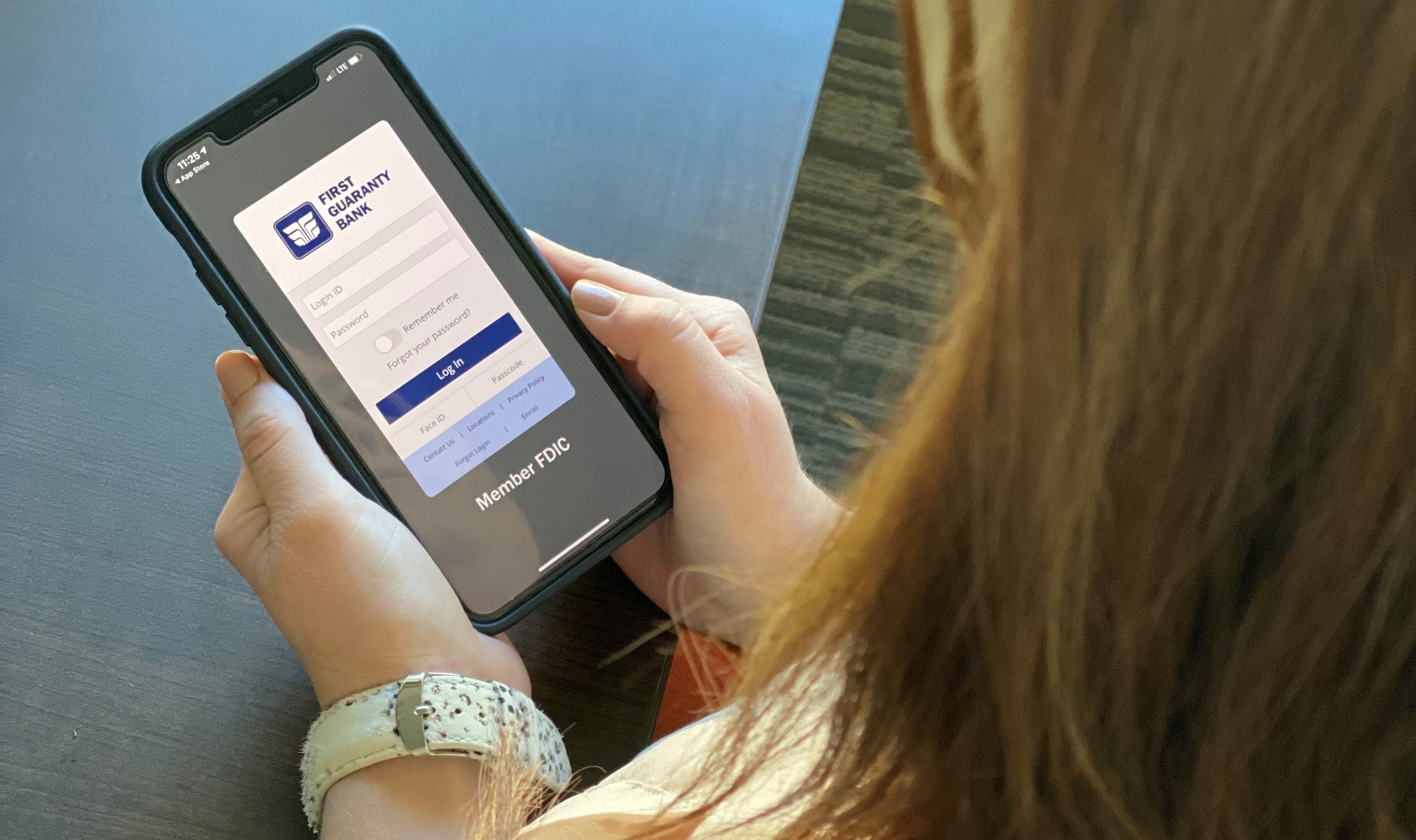 Woman Holding iPhone with the My FGB App Login on Screen