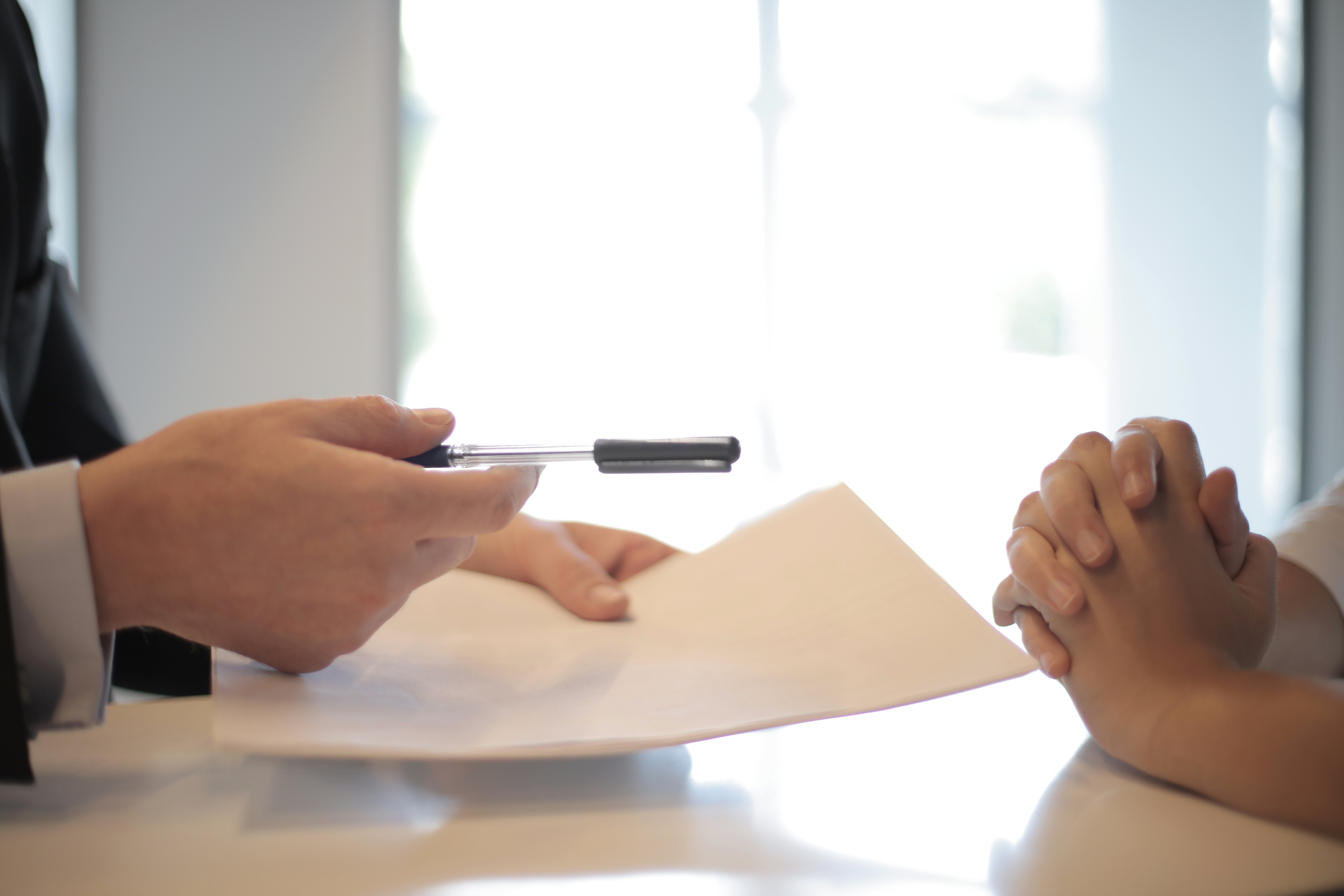 Man Holding Papers and Pens Across from Person