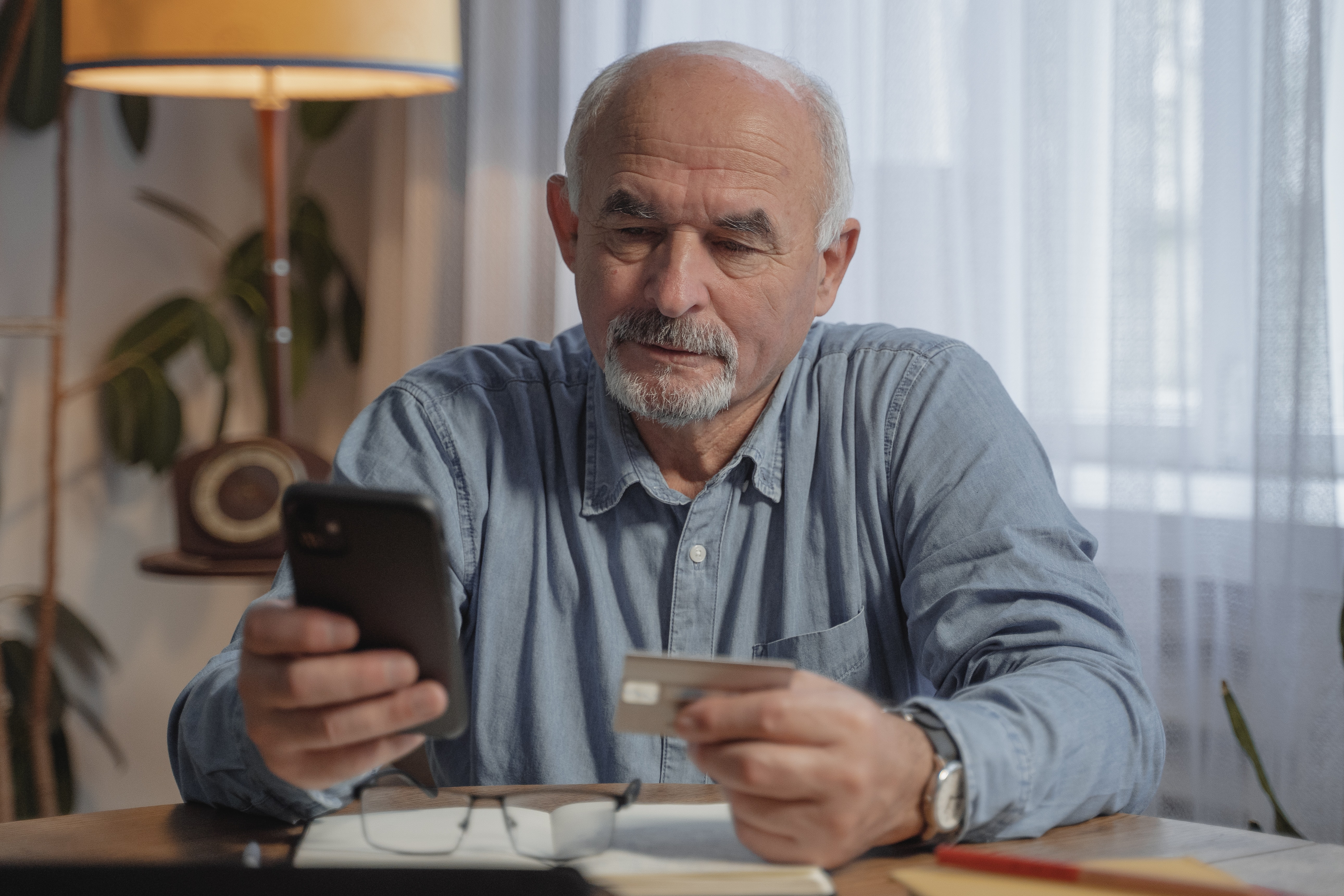 Older Man Looking at Phone and Debit Card