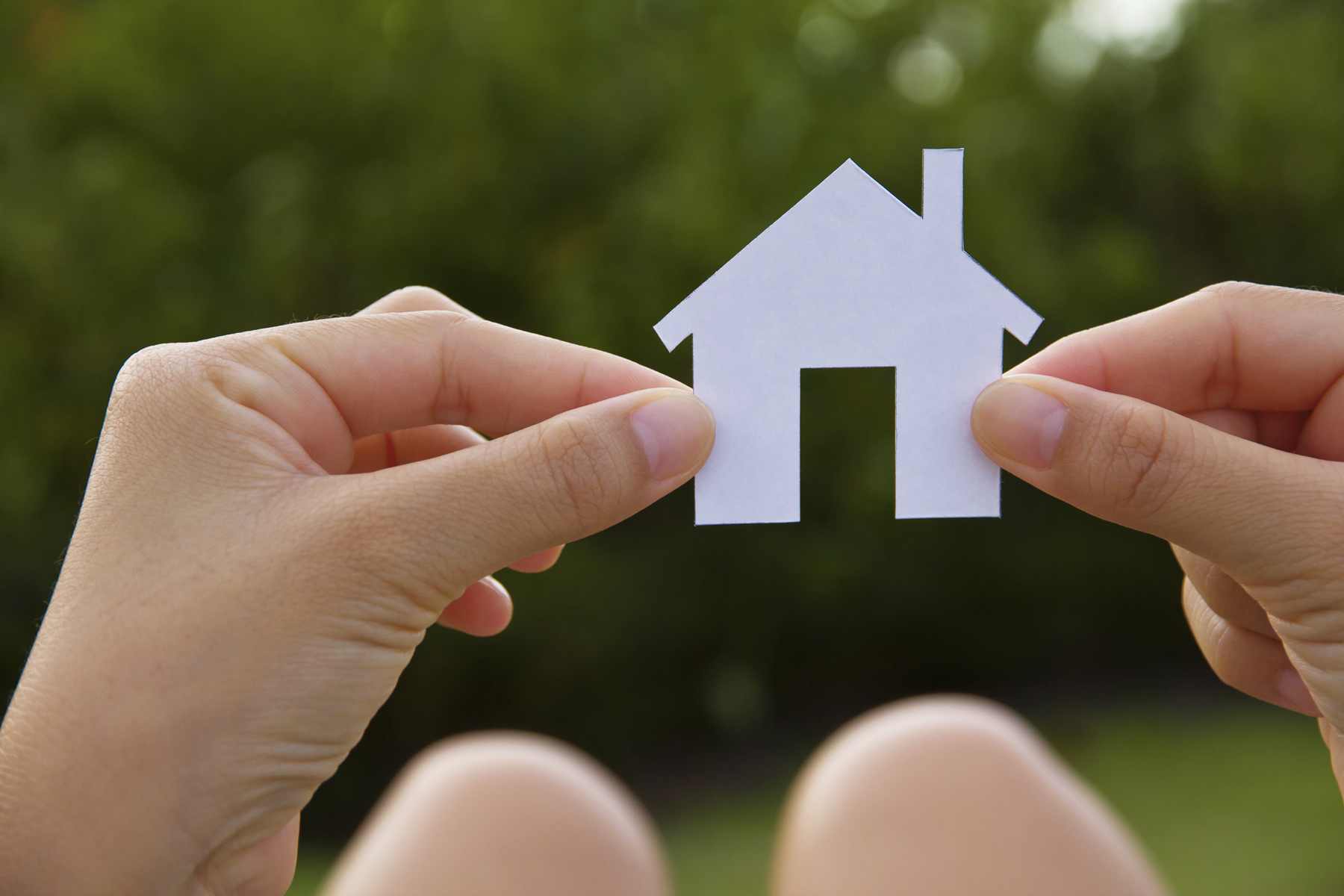 Hands Holding a White Paper Cut out of a House