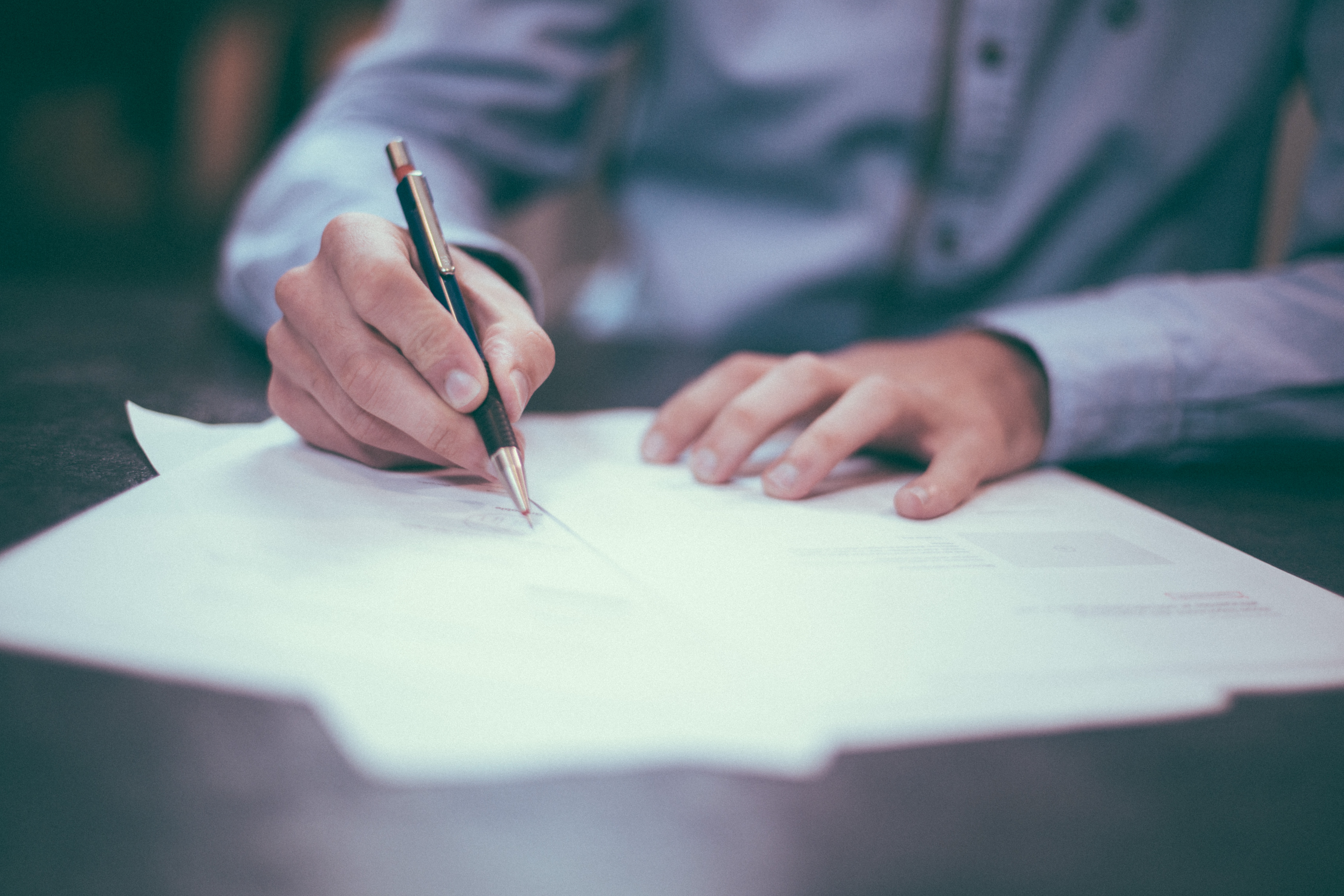 Person Signing Stack of Papers