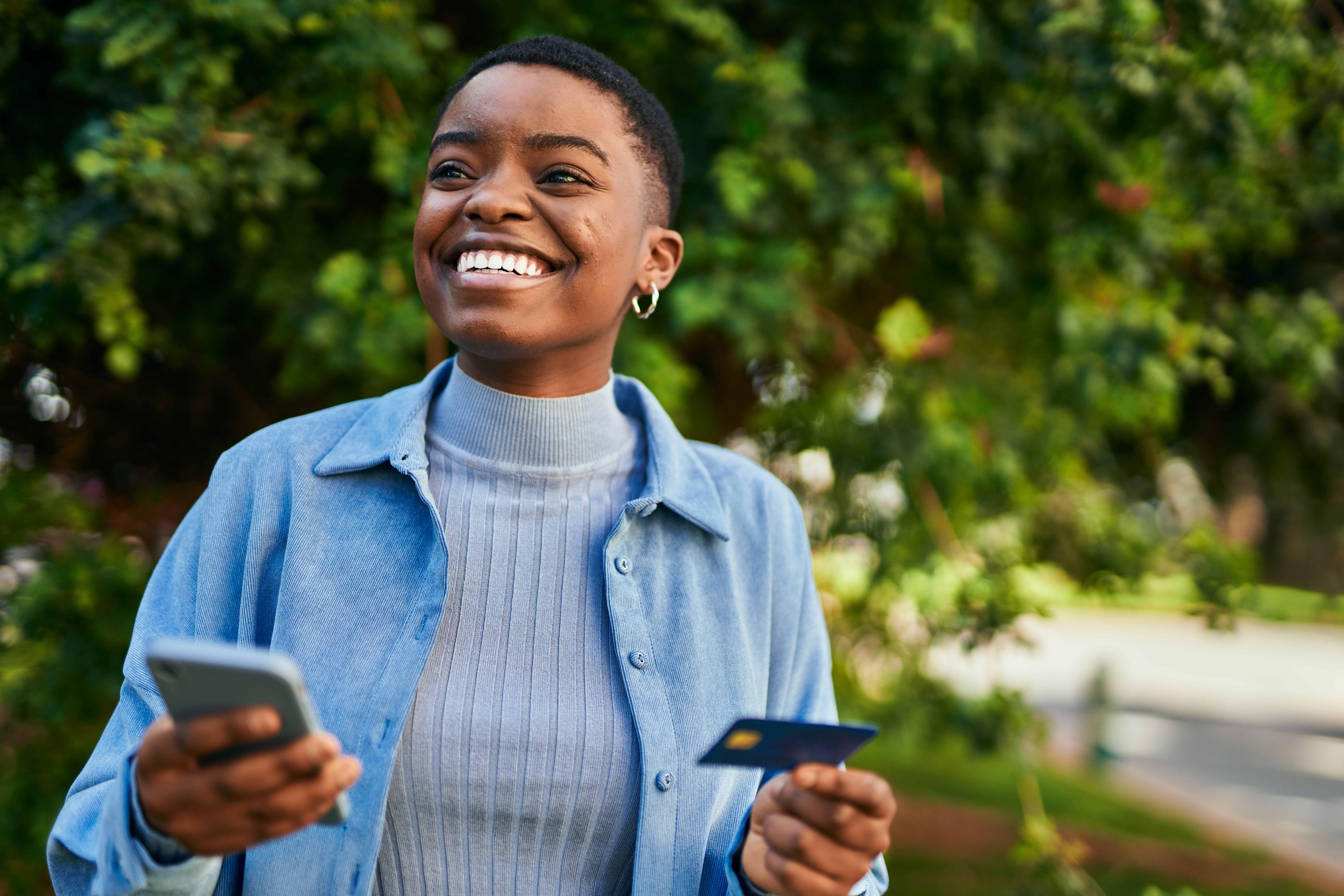 A person holding a credit card and a phone.