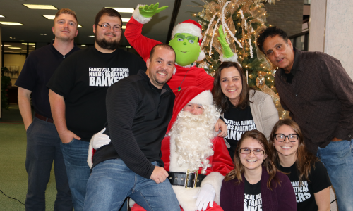 photo of employees posing with Santa at Christmas branch event